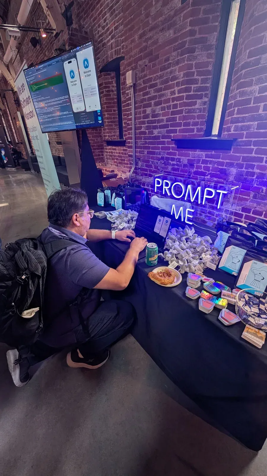 The Expo booth at Chain React, with a neon PROMPT ME sign above the table